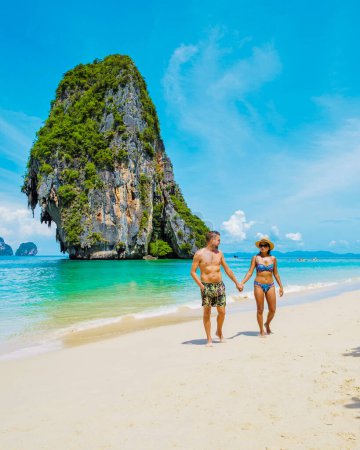 Foto de Railay Beach Krabi Tailandia, la playa tropical de Railay Krabi, un par de hombres y mujeres en la playa, Vista panorámica de la idílica playa de Railay en Tailandia con un barco largo tradicional. - Imagen libre de derechos