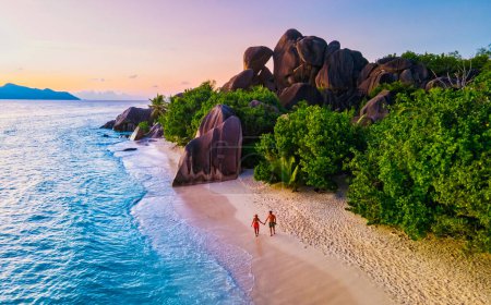 Photo for Anse Source dArgent beach, La Digue Island, Seyshelles, Drone aerial view of La Digue Seychelles bird eye view.of tropical Island, couple men and woman walking at the beach during sunset at a luxury - Royalty Free Image