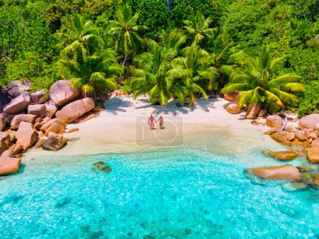 Foto de Anse Lazio Praslin Seychelles, a young couple of men and women on a tropical beach during a luxury vacation in Seychelles. Tropical beach Anse Lazio Praslin Seychelles - Imagen libre de derechos