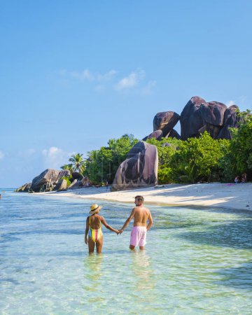 Foto de Anse Source dArgent, La Digue Seychelles, a young couple of men and women on a tropical beach during a luxury vacation in Seychelles. Tropical beach Anse Source dArgent, La Digue Seychelles - Imagen libre de derechos