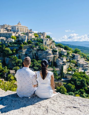 Téléchargez les photos : Un couple d'hommes et de femmes en vacances dans le sud de la France avec vue sur le vieux village historique de Gordes Luberon Provence pendant l'été - en image libre de droit