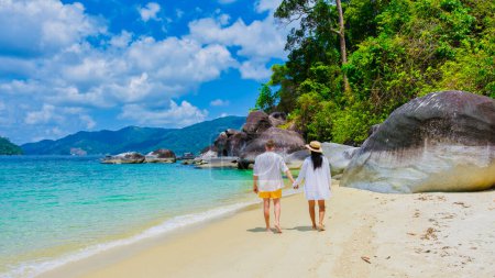 Téléchargez les photos : Couple d'hommes et de femmes sur la plage en maillots de bain à l'île de Koh Adang près de l'île de Koh Lipe en Thaïlande du Sud, avec turqouse couleur océan et plage de sable blanc Tarutao National Park - en image libre de droit