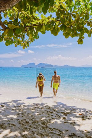 Téléchargez les photos : Un couple d'hommes et de femmes marchant sur la plage de l'île de Koh Kradan en Thaïlande pendant les vacances par une journée ensoleillée - en image libre de droit