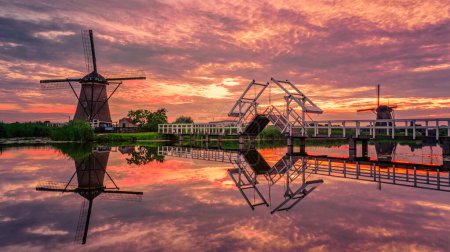 Photo for Windmill village Kinderdijk in the Netherlands during sunset, wooden historical mill at sunset - Royalty Free Image