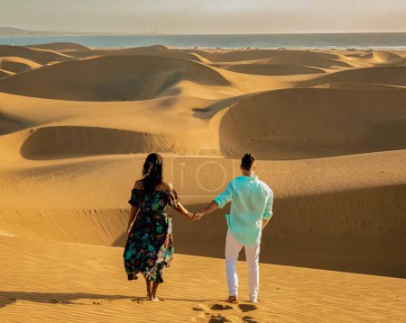Foto de Pareja caminando por las dunas de arena del desierto de Maspalomas Gran Canaria, hombres y mujeres observando amanecer en el desierto de Maspalomas Gran Canaria - Imagen libre de derechos