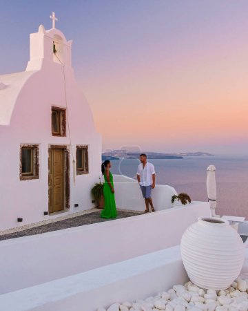 Téléchargez les photos : Couple regardant le coucher du soleil en vacances à Santorin en Grèce, hommes et femmes regardant le village avec des églises blanches et des dômes bleus en Grèce. - en image libre de droit
