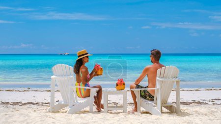 Téléchargez les photos : Couple hommes et femmes sur la plage avec boisson à la noix de coco Praslin Seychelles île tropicale avec withe plages et palmiers, la plage de l'Anse Volbert Seychelles. - en image libre de droit