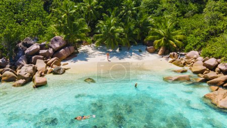 Foto de Anse Lazio Praslin Seychelles, a young couple of men and women on a tropical beach during a luxury vacation in Seychelles. Tropical beach Anse Lazio Praslin Seychelles - Imagen libre de derechos