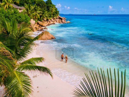 Photo for Anse Patates, La Digue Seychelles, a young couple of men and women on a tropical beach during a luxury vacation in Seychelles. Tropical beach Anse Patates, La Digue Seychelles - Royalty Free Image