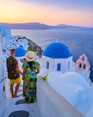 Photo for A couple walking at the village of Oia Santorini Greece, men and women visit the whitewashed Greek village of Oia during summer vacation - Royalty Free Image