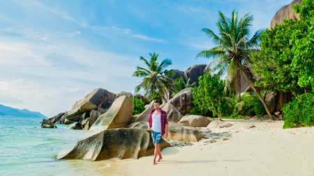 Téléchargez les photos : Young men walking at a white tropical beach Anse Source dArgent beach La Digue Seychelles Islands. - en image libre de droit
