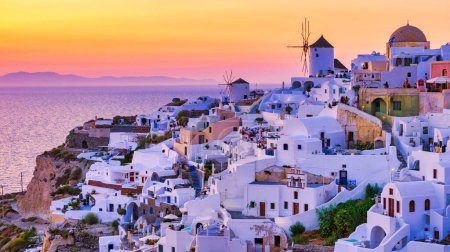 Foto de Sunset with white churches an blue domes by the ocean of Oia Santorini Greece. - Imagen libre de derechos