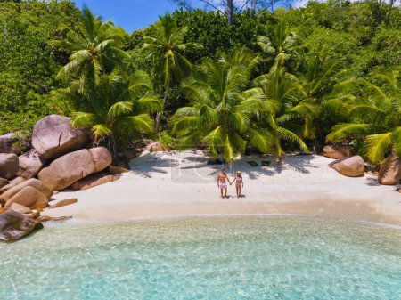 Foto de Anse Lazio Praslin Seychelles, una joven pareja de hombres y mujeres en una playa tropical durante unas vacaciones de lujo en Seychelles. Playa tropical Anse Lazio Praslin Seychelles - Imagen libre de derechos