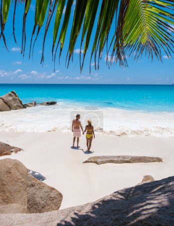 Foto de Anse Lazio Praslin Seychelles, una joven pareja de hombres y mujeres en una playa tropical durante unas vacaciones de lujo en Seychelles. - Imagen libre de derechos