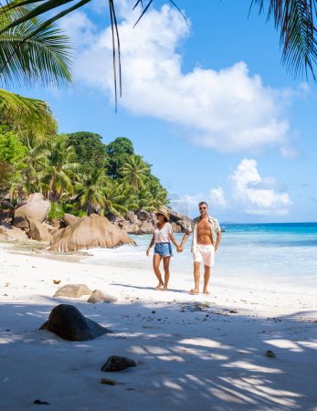 Foto de Una joven pareja de hombres y mujeres en una playa tropical durante unas vacaciones de lujo en las Seychelles. Playa tropical Anse Lazio Praslin Islas Seychelles - Imagen libre de derechos