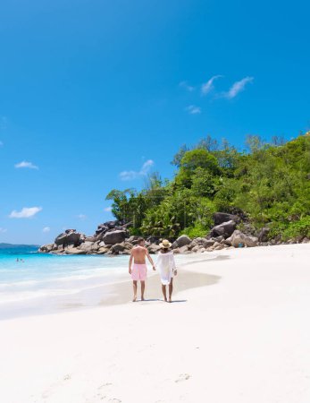 Téléchargez les photos : Anse Lazio Praslin Seychelles un jeune couple d'hommes et de femmes sur une plage tropicale pendant des vacances de luxe. Plage tropicale Anse Latium Praslin Îles Seychelles par une journée ensoleillée avec un ciel bleu - en image libre de droit