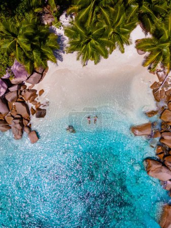Foto de Anse Lazio Praslin Seychelles un joven par de hombres y mujeres en una playa tropical durante unas vacaciones de lujo allí. Playa tropical Anse Lazio Praslin Islas Seychelles en un día soleado con un cielo azul - Imagen libre de derechos