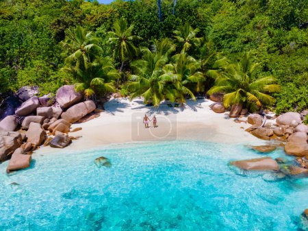 Téléchargez les photos : Anse Lazio Praslin Seychelles un jeune couple d'hommes et de femmes sur une plage tropicale pendant des vacances de luxe. Plage tropicale Anse Latium Praslin Îles Seychelles par une journée ensoleillée avec un ciel bleu - en image libre de droit
