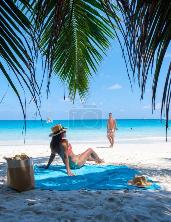 Foto de Anse Lazio Praslin Seychelles un joven par de hombres y mujeres en una playa tropical durante unas vacaciones de lujo allí. Playa tropical Anse Lazio Praslin Islas Seychelles en un día soleado con un cielo azul - Imagen libre de derechos