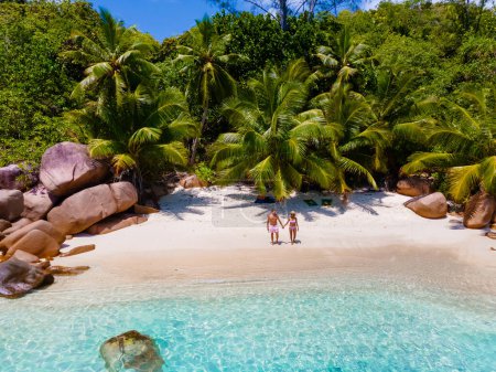 Téléchargez les photos : Anse Lazio Praslin Seychelles, un jeune couple d'hommes et de femmes sur une plage tropicale pendant des vacances de luxe aux Seychelles. Plage tropicale Anse Latium Praslin Seychelles Drone Vue aérienne - en image libre de droit