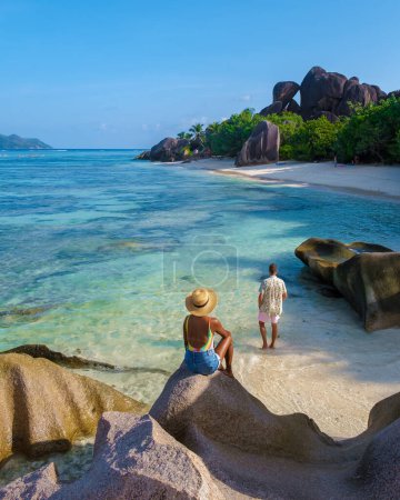 Foto de Una joven pareja de hombres y mujeres en una playa tropical durante unas vacaciones de lujo en Seychelles. Playa tropical Anse Source dArgent, La Digue Seychelles - Imagen libre de derechos