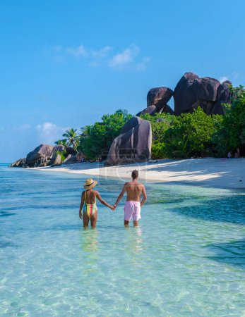 Foto de Una joven pareja de hombres y mujeres en una playa tropical durante unas vacaciones de lujo en Seychelles. Playa tropical Anse Source dArgent, La Digue Seychelles - Imagen libre de derechos