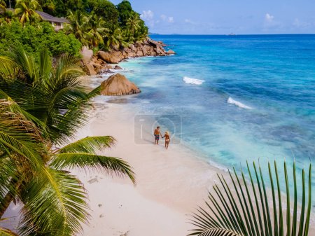 Téléchargez les photos : Anse Patates, La Digue Seychelles, un jeune couple d'hommes et de femmes sur une plage tropicale pendant des vacances de luxe aux Seychelles. Plage tropicale Anse Patates, La Digue Seychelles drone vue aérienne - en image libre de droit
