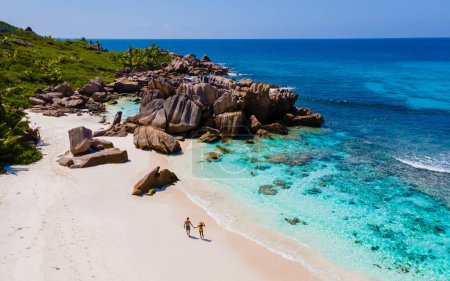 Téléchargez les photos : Hommes et femmes sur la plage d'Anse Cocos La Digue Seychelles, un jeune couple sur une plage tropicale pendant des vacances de luxe aux Seychelles. Plage tropicale Anse Cocos La Digue Seychelles. - en image libre de droit