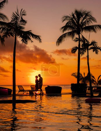 Foto de Una pareja joven de hombres y mujeres en una piscina durante unas vacaciones en una isla tropical. hombre y mujer en piscina infinita durante el atardecer. vacaciones de lujo en Mauricio - Imagen libre de derechos