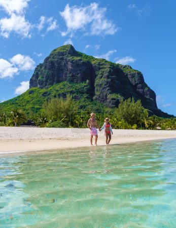 Foto de Hombre y mujer en una playa tropical en Mauricio, una pareja de vacaciones de luna de miel en Mauricio Le Morne Beach con Le Morne Mountain al fondo - Imagen libre de derechos