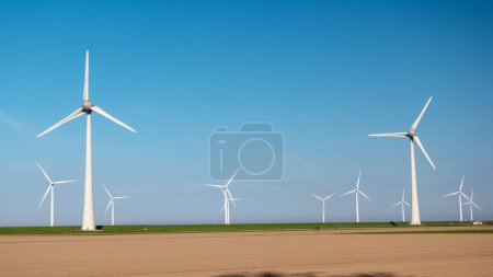 Foto de Parque de molinos de viento con nubes y un cielo azul, parque de molinos de viento en el océano vista aérea del paisaje verde con turbinas de molinos de viento - Imagen libre de derechos
