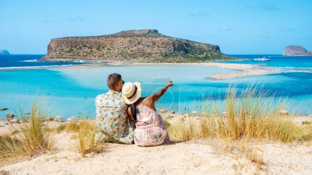 Foto de Creta Grecia, laguna de Balos Isla de Creta, Grecia. Los turistas se relajan en el océano cristalino de la playa de Balos. un par de hombres y una mujer visitan la playa durante unas vacaciones en Grecia en un día soleado - Imagen libre de derechos