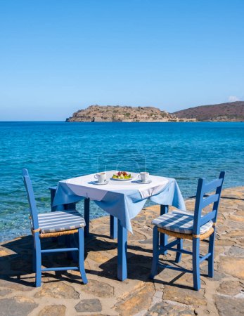 Foto de Creta Grecia Plaka Lassithi, una mesa azul tradicional y sillas en la playa de Creta Grecia. Paralia Plakas, pueblo de Plaka Creta. - Imagen libre de derechos