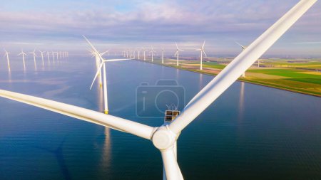 Foto de Parque de molinos de viento en alta mar con nubes y un cielo azul, parque de molinos de viento en la vista aérea del océano con turbina eólica Flevoland Países Bajos Ijsselmeer. Energía verde en los Países Bajos en un día soleado - Imagen libre de derechos
