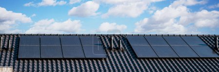 Foto de Paneles solares unidos en el techo contra un cielo soleado Primer plano de un edificio nuevo con paneles solares negros. Zonnepanelen, Zonne energie, Traducción: Panel solar,, Sun Energy - Imagen libre de derechos