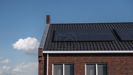 Foto de Casas de nueva construcción con paneles solares unidos en el techo contra un cielo soleado, Primer plano de un nuevo edificio con paneles solares negros en los Países Bajos - Imagen libre de derechos