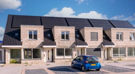 Téléchargez les photos : Maisons nouvellement construites avec des panneaux solaires fixés sur le toit contre un ciel ensoleillé. panneaux solaires noirs sur un toit - en image libre de droit