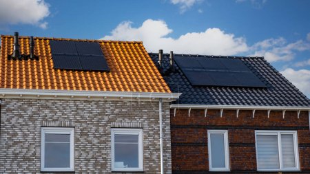 Foto de Casas de nueva construcción con paneles solares unidos en el techo contra un cielo soleado. paneles solares negros en un techo - Imagen libre de derechos