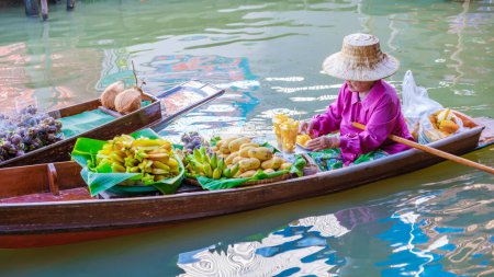 Foto de Agosto 2023, tenedores de puestos de mercado en pequeñas embarcaciones que venden frutas y verduras locales, Damnoen Saduak Floating Market, Tailandia - Imagen libre de derechos