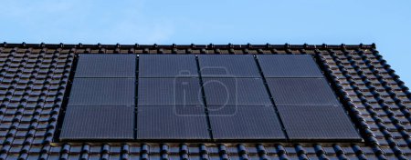 Foto de Casas de nueva construcción con paneles solares negros en el techo contra un cielo soleado Primer plano de un edificio nuevo con paneles solares negros. Zonnepanelen, Zonne energie, Traducción: Panel solar,, Sun Energy - Imagen libre de derechos