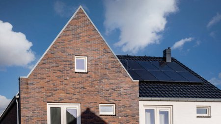 Téléchargez les photos : Maisons nouvellement construites avec des panneaux solaires fixés sur le toit, panneaux solaires sur un toit à pignon. Belle, grande maison moderne et énergie solaire. - en image libre de droit