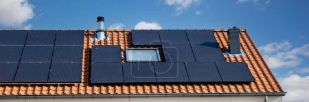 Téléchargez les photos : Maisons nouvellement construites avec des panneaux solaires fixés au toit, photovoltaïque sur le toit rouge d'une maison, et une source d'électricité alternative. Concept de ressources durables - en image libre de droit