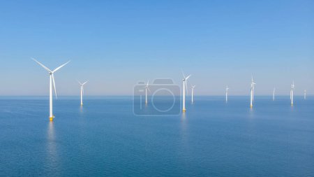 Photo for Windmill park with clouds and a blue sky, windmill park in the ocean aerial view with wind turbine Flevoland Netherlands Ijsselmeer. Green Energy production in the Netherlands on a sunny day - Royalty Free Image