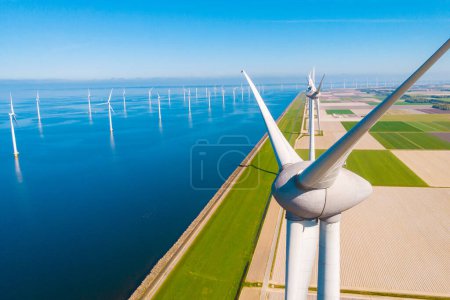 Photo for Wind mill turbines with a blue sky, windmill park in the ocean aerial view with wind turbine Flevoland Netherlands Ijsselmeer. Green Energy production in the Netherlands - Royalty Free Image