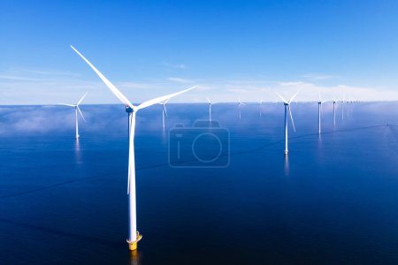 Foto de Drone Vista aérea en el parque de molinos de viento con turbinas de molinos de viento en el océano con un cielo azul - Imagen libre de derechos