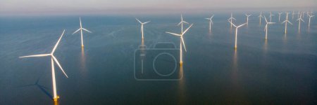 Foto de Parque de molinos de viento con nubes y cielo azul, parque de molinos de viento en la vista aérea del océano con turbina eólica verde Producción de energía en los Países Bajos - Imagen libre de derechos