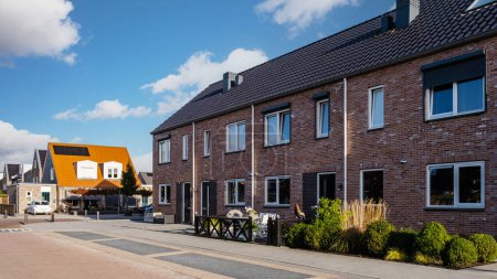 Foto de Zona suburbana holandesa con casas familiares modernas, casas familiares modernas de nueva construcción en los Países Bajos, barrio agradable y cómodo. Algunas casas en la calle vacía en los suburbios de Urk Flevoland - Imagen libre de derechos