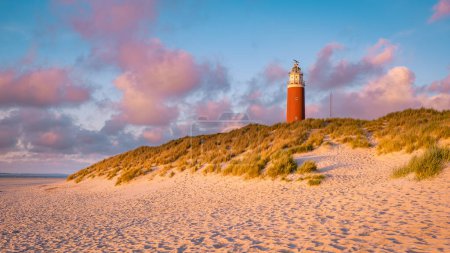 Téléchargez les photos : Phare de Texell au coucher du soleil Pays-Bas Île hollandaise Texel en été avec dunes de sable à l'île des Wadden en soirée - en image libre de droit