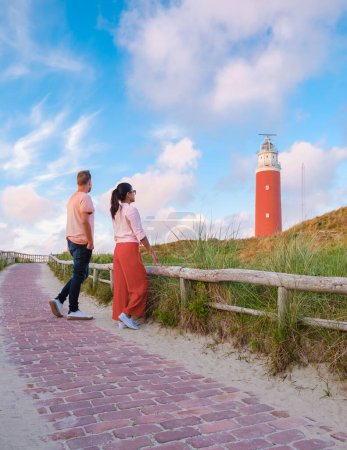 Foto de Una pareja visita el faro de Texel durante la puesta del sol Países Bajos Dutch Island Texel Holland, la pareja visita el faro, hombres y mujeres de vacaciones Texel - Imagen libre de derechos