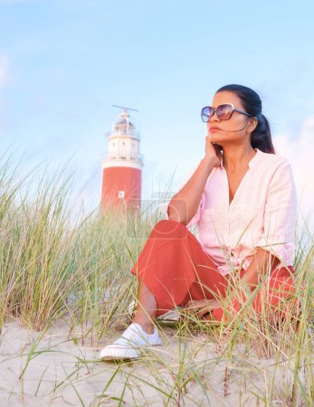 Photo for Texel lighthouse during sunset Netherlands Dutch Island Texel Holland, Asian woman visit the lighthouse during vacation at the Dutch Island Texel - Royalty Free Image